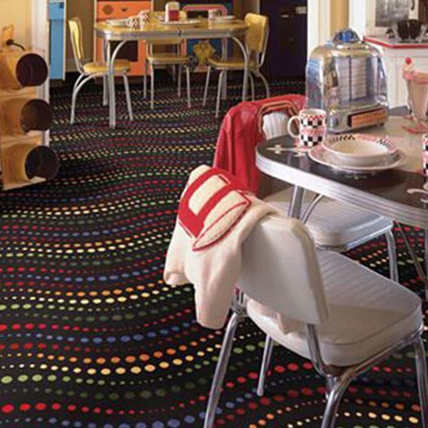 Shaw Hot Spot Carpet, Disco Fever — black carpet with colorful wavy polka dot pattern in a retro diner room