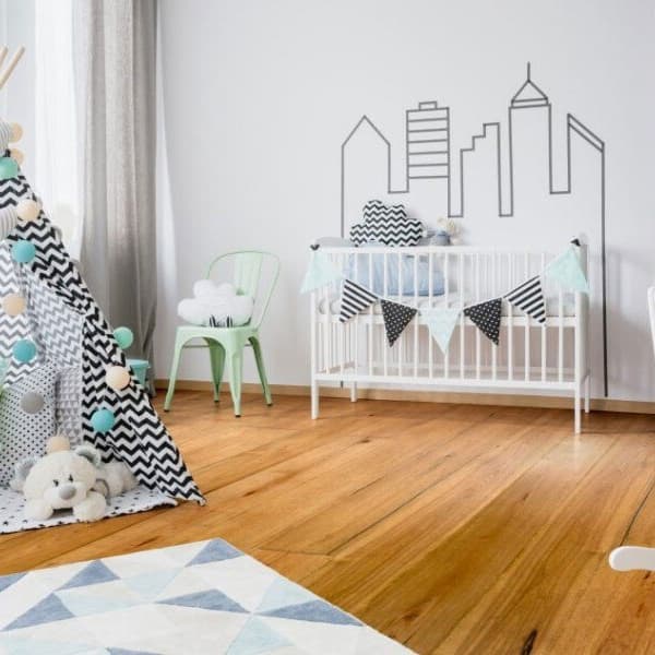 Engineered hardwood in child's bedroom with white crib and chevron pattern hut.