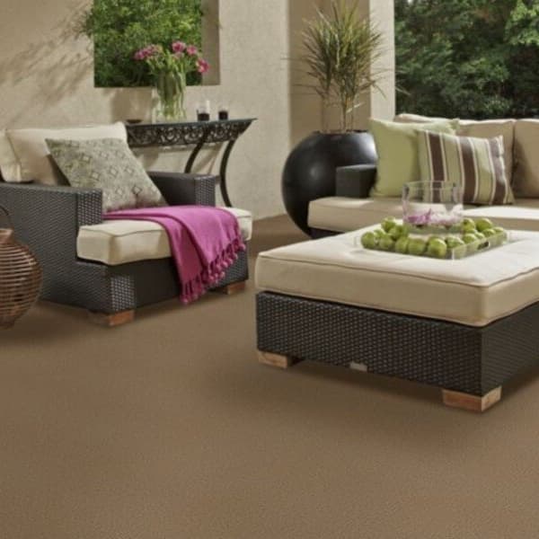 Shaw Bedecked Outdoor Carpet in Driftwood — patio with wicker furniture and beige cushions on textured brown carpet surface