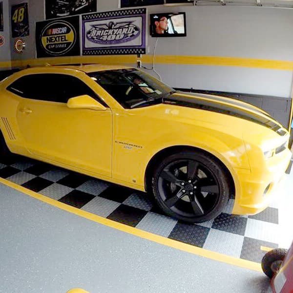 Grid-loc diamond garage floor tiles in black and gray checkboard custom design in garage with yellow Chevrolet Camaro parked on them.