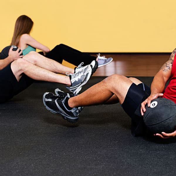 Home gym with black recycled rubber flooring under people doing sit-ups