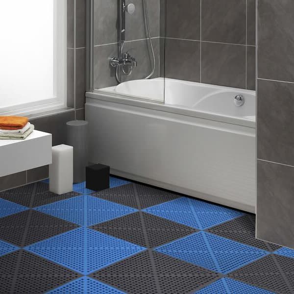 Drainage tiles in blue and black checkboard pattern in a bathroom with gray walls and white bathtub.
