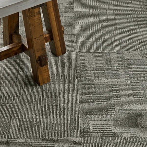 Pentz Blockade Carpet Tiles, Gridlock pattern — gray textured carpet tile installation under a wooden table leg