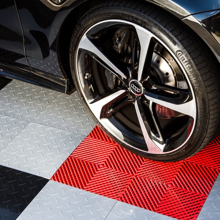 Nitro Tiles garage floor tiles in red and gray with diamond plate pattern under a car tire