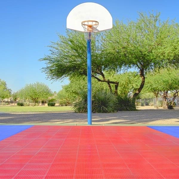 ProGame Outdoor Basketball Court Kit — red and blue tiles, installed in a backyard setting under a basketball hoop