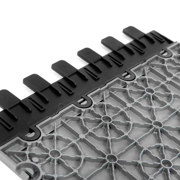 Nitro Tile Expansion Joint — black polypropylene edge strip attached to gray tile with geometric grid pattern, close-up view
