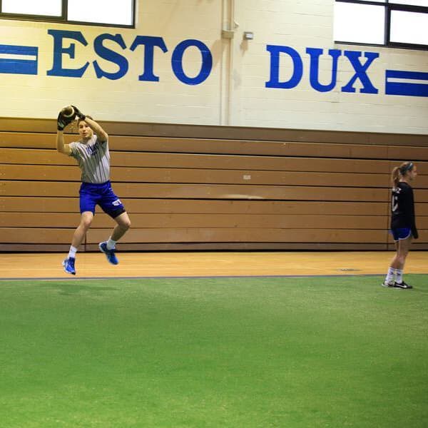 Sports field turf used in a school gym with athlete catching a football.