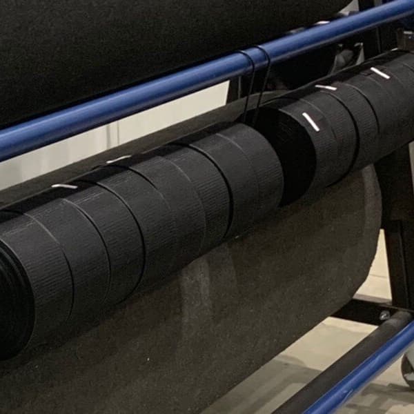 Gym floor cover seam tape storage unit with black rolls on blue bars