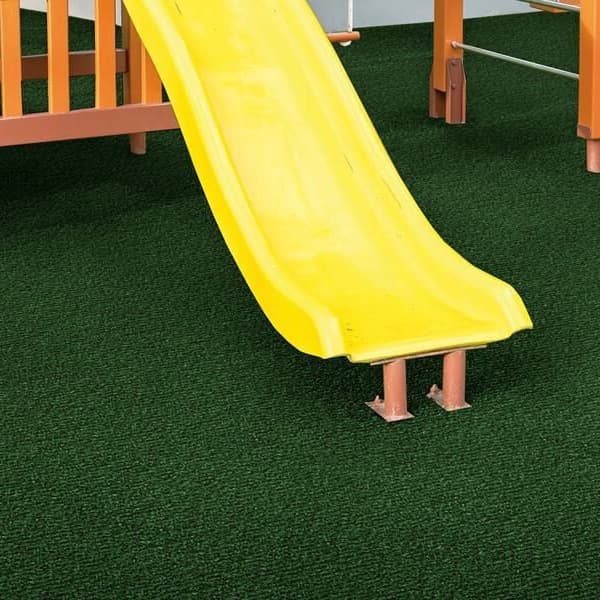 Foss Green Lawn Turf Rolls — artificial grass under a yellow slide and wooden play structure in a playground setting