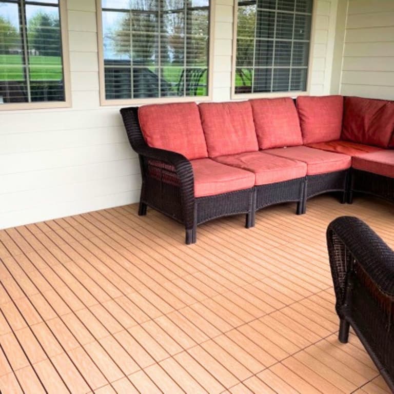 Outdoor patio with NewTechWood UltraShield deck tiles in Peruvian Teak, featuring a wicker sectional sofa with red cushions