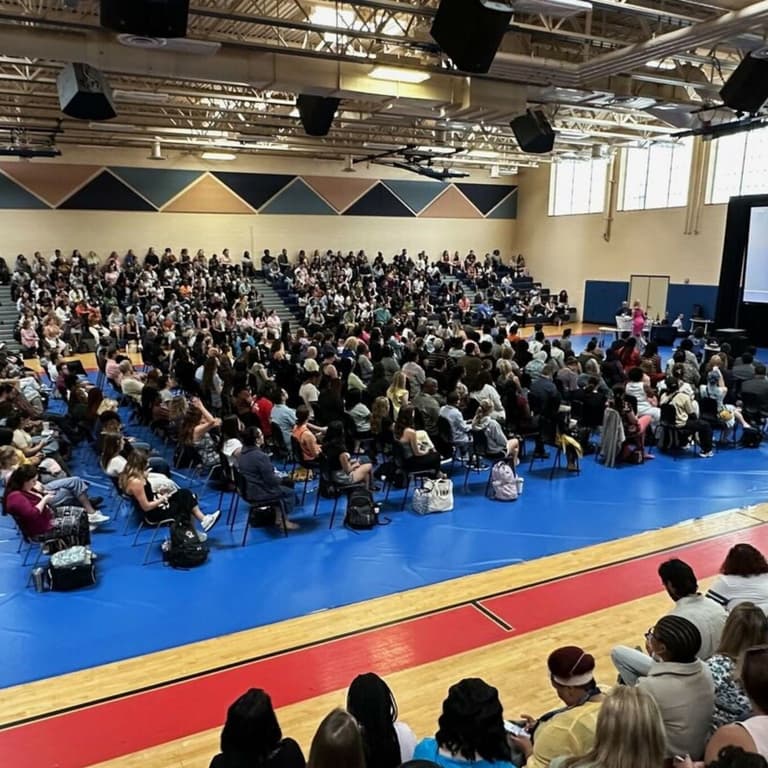 Gymnasium with royal blue floor covering, audience seated on bleachers