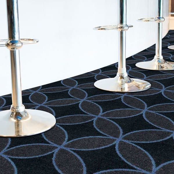 Joy Carpets Eclipse Carpet, charcoal with blue geometric pattern, in a commercial space with bar stools