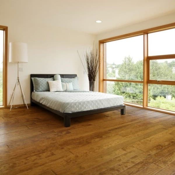 Engineered hardwood planks in a minimalist cozy bedroom with large windows.