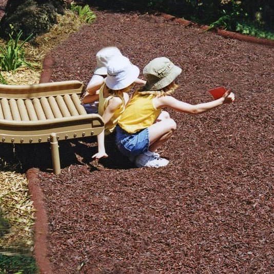 Playground with brown premium rubber mulch flooring next to a slide