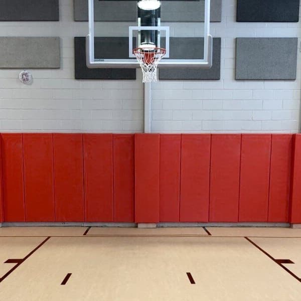Red wall pads in gymnasium behind basketball hoop.