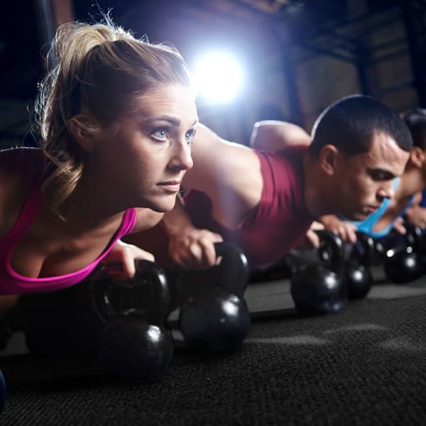 Rubber floor tiles in commercial gym with a group fitness class performing kettlebell push-ups.