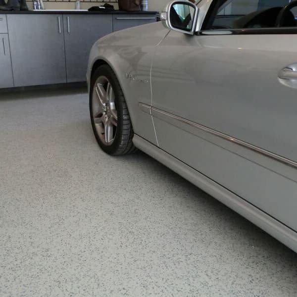 Epoxy garage flooring in garage with gray car parked.