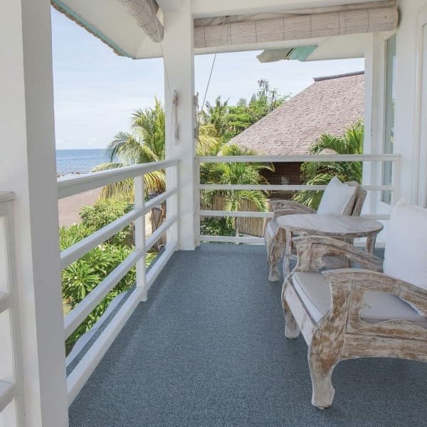 Carpet tiles on an outdoor patio with wooden chairs overlooking the ocean.