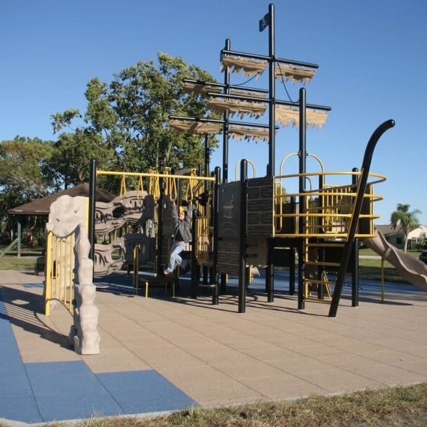 PlayTime Interlocking Playground Tiles, blue and tan, installed under a pirate ship playground structure