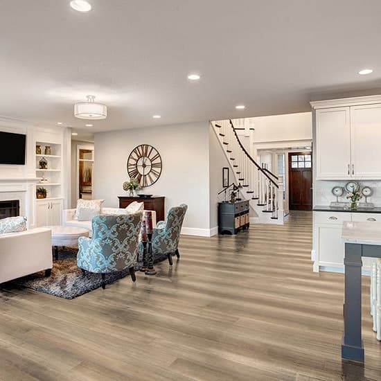 Engineered hardwood in an open-concept living room and kitchen with white cabinetry and modern furniture.