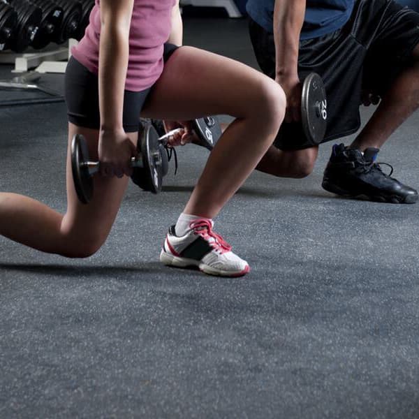 Rubber gym flooring rolls in gym with man and woman doing lunges.