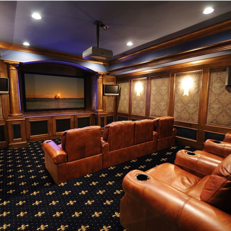 Home theater with navy carpet featuring gold fleur-de-lis pattern under leather recliners
