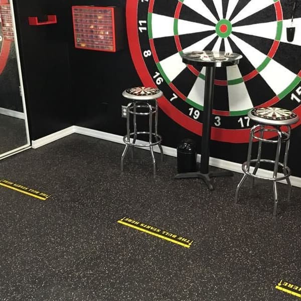 Game room with Eco-Lock Rubber Tiles in black speckled finish, featuring dartboard wall and bar stools