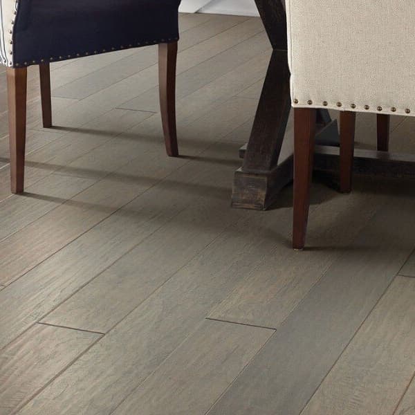 Shaw Riverstone Hickory Engineered Wood, Sterling — dining room floor with wooden chairs and table legs visible