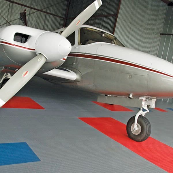 White plane in hangar with gray, blue, and red coin flex tiles.
