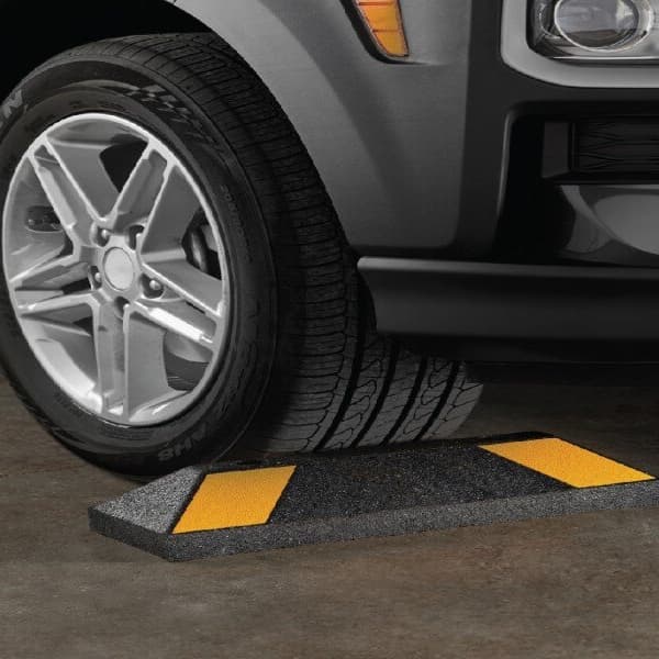 Rubberific Parking Stop, black with yellow stripes — car tire resting on parking stop in driveway