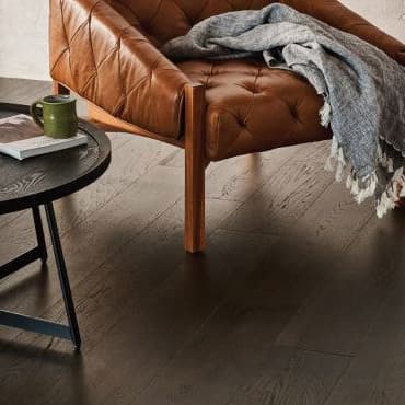 Brown chair and black table on dark hardwood planks.