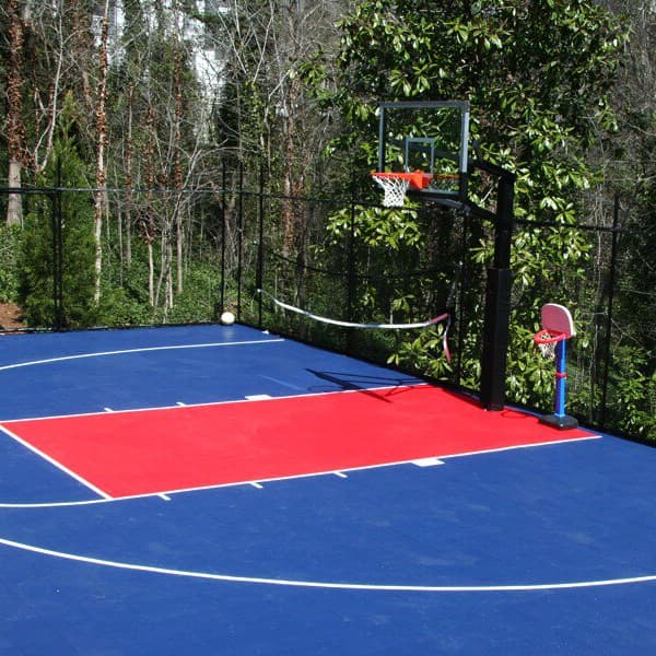 Outdoor basketball court with blue and red sports tiles, white court lines, hoop, and surrounding fence
