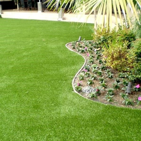 Newport Turf Rolls, Olive/Field Green — artificial grass lawn with curved garden bed and palm trees