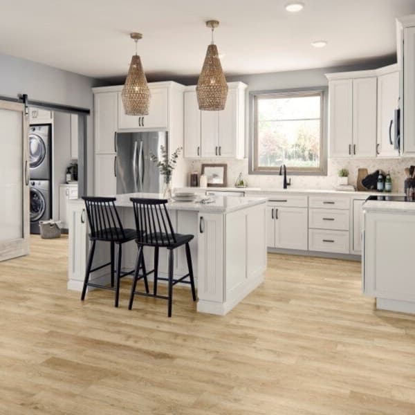 Modern kitchen with white cabinetry and island, featuring Mannington Realta 7" rigid core vinyl planks in Oak Natural