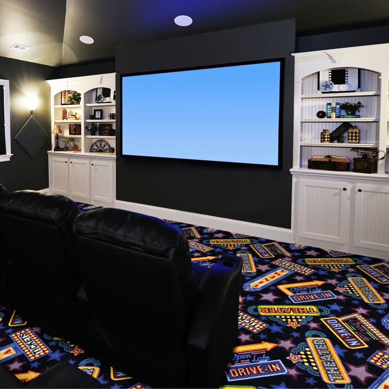 Home theater room with Joy Carpets Theater District carpet featuring vibrant blue, yellow, and red retro movie marquee