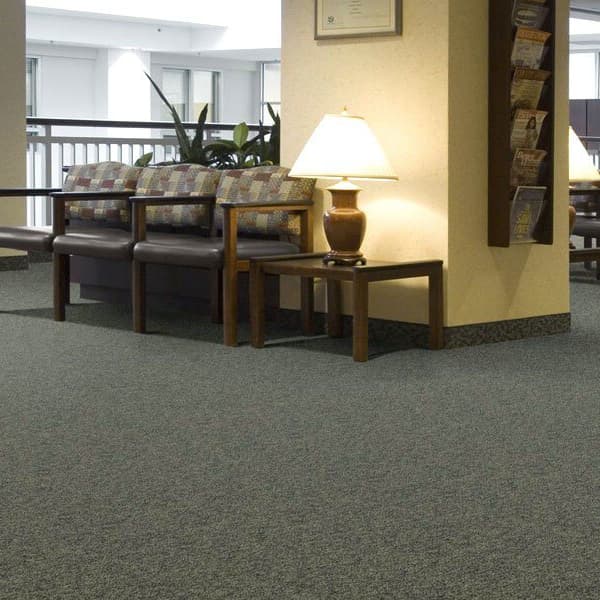 Shaw No Limits Carpet Tile — gray textured carpet tile in a waiting area with wooden chairs and side tables