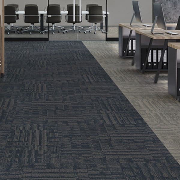 Office space with J&J Flooring Outfitter Carpet Plank in dark gray and light gray patterns, installed under desks and