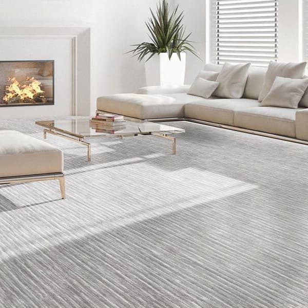 Joy Carpets Balanced Carpet, Morning Fog — living room with light gray textured carpet under a sectional sofa and glass