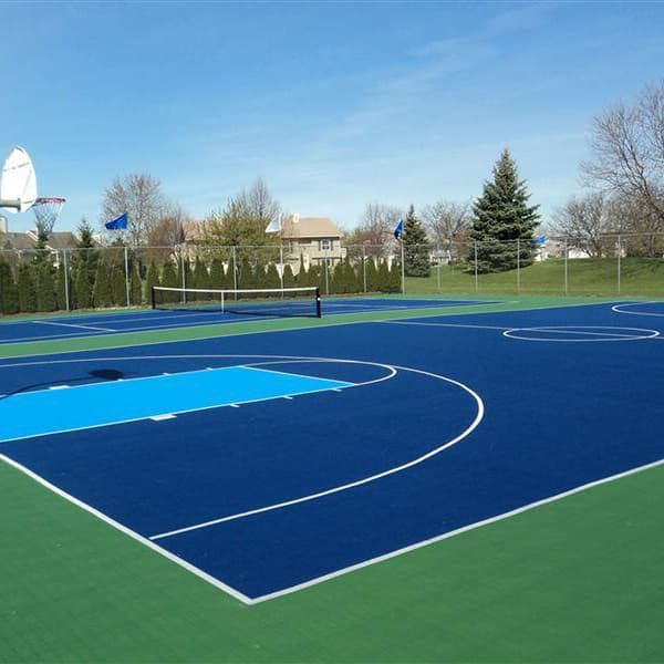 Outdoor basketball court with Mateflex II Court Tiles in Performance Blue and green, featuring white lines and hoops
