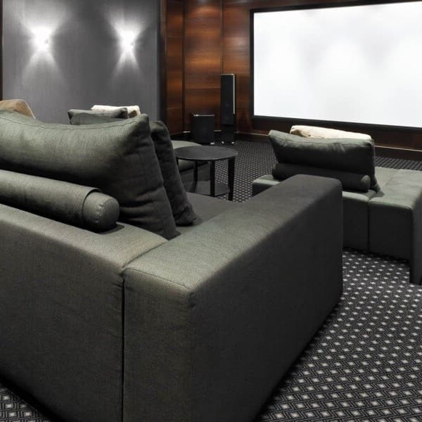 Home theater with Joy Carpets Diamond Lattice carpet in Charcoal, featuring a geometric pattern under dark gray sectional