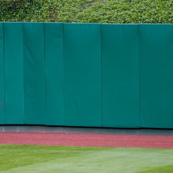 4' x 8' Pro-Series Outdoor Wall Pads — green, installed along a sports field fence with grass and red track below