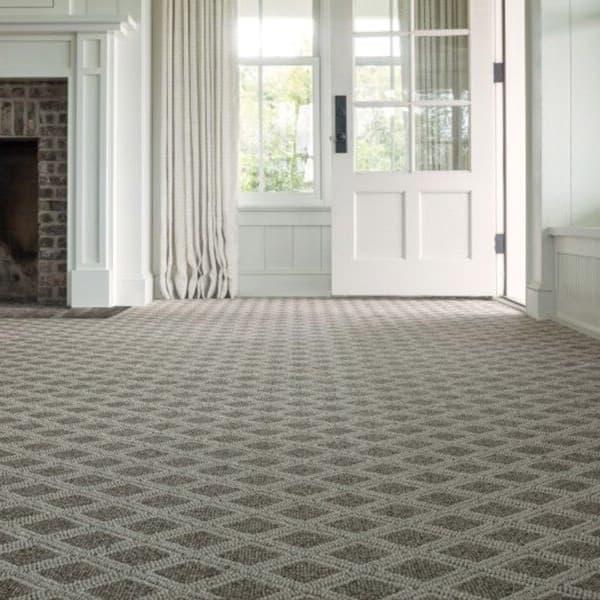 Patterned carpet flooring in an elegant living room with brick fireplace and large windows.