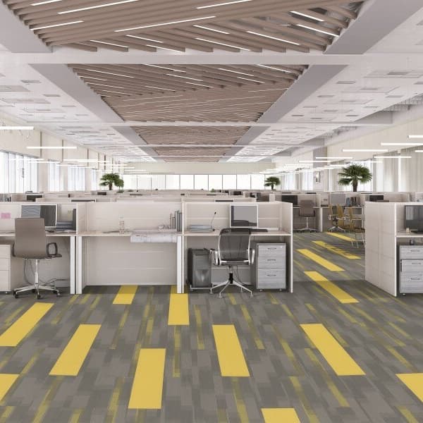 Open office space with Pentz Amplify carpet planks in gray and yellow abstract pattern under cubicles
