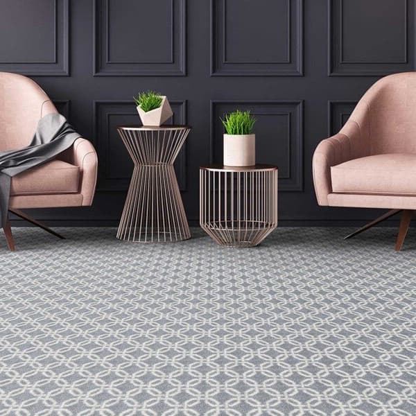 Joy Carpets Intersect Carpet, Cloudy — living room with geometric patterned nylon carpet under two pink armchairs and metal