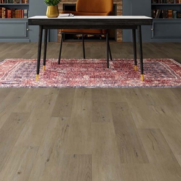 Mannington Adura 7" rigid waterproof plank flooring in a taupe oak finish, installed in a room with a desk and rug