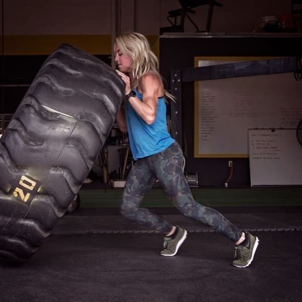 Woman lifting tire in commercial gym.
