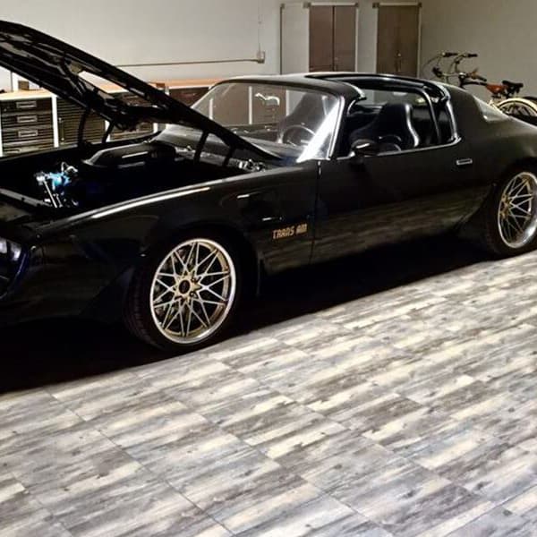 Garage with black classic car on Swisstrax Vinyltrax tiles in Reclaimed Pine pattern