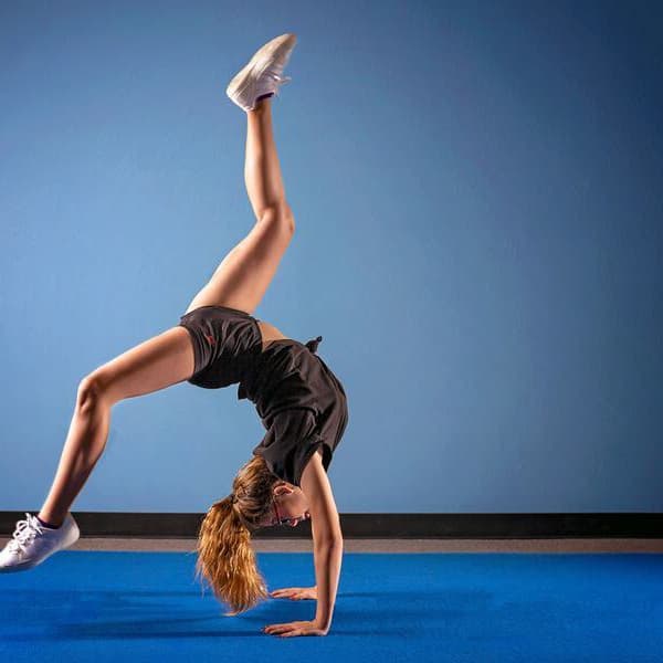 Girl performing handstand on blue Home Cheer Mat in gym setting